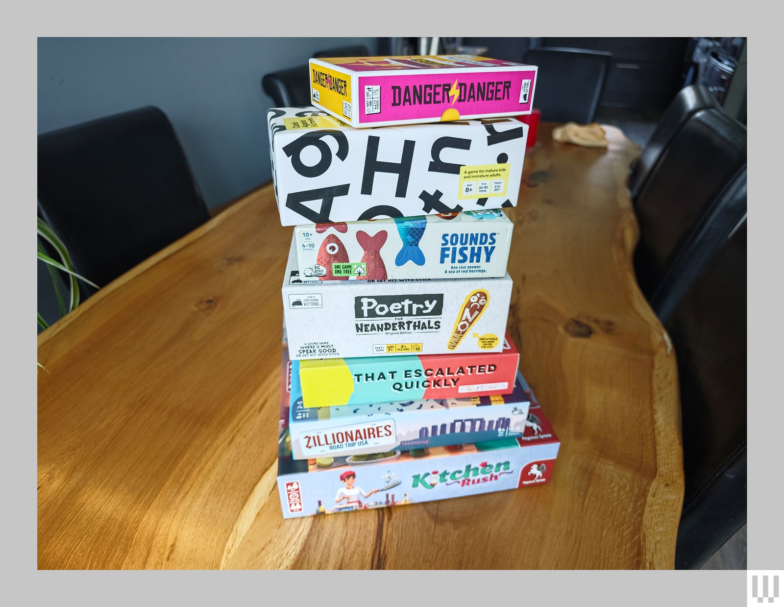 Stack of board game boxes on a large wooden table