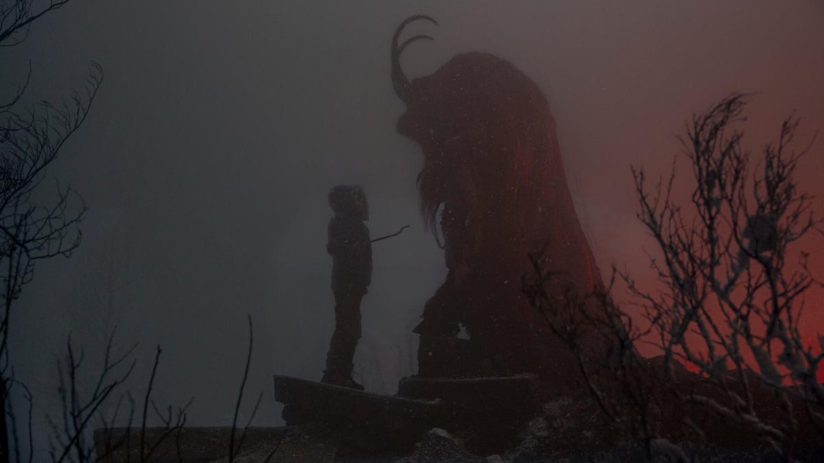 in a scene from the movie Krampus, a young person stands in front of a giant monster in the silhouette of a dark fog