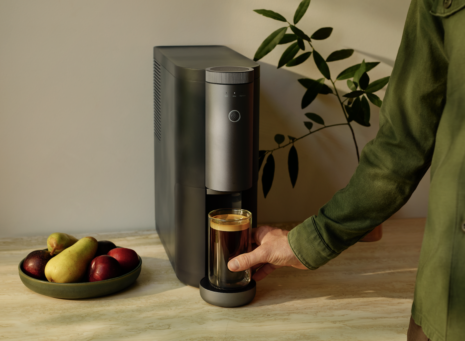 The Cumulus machine is a black rectangular cold brew coffee maker with rounded edges placed on a wooden counter while...